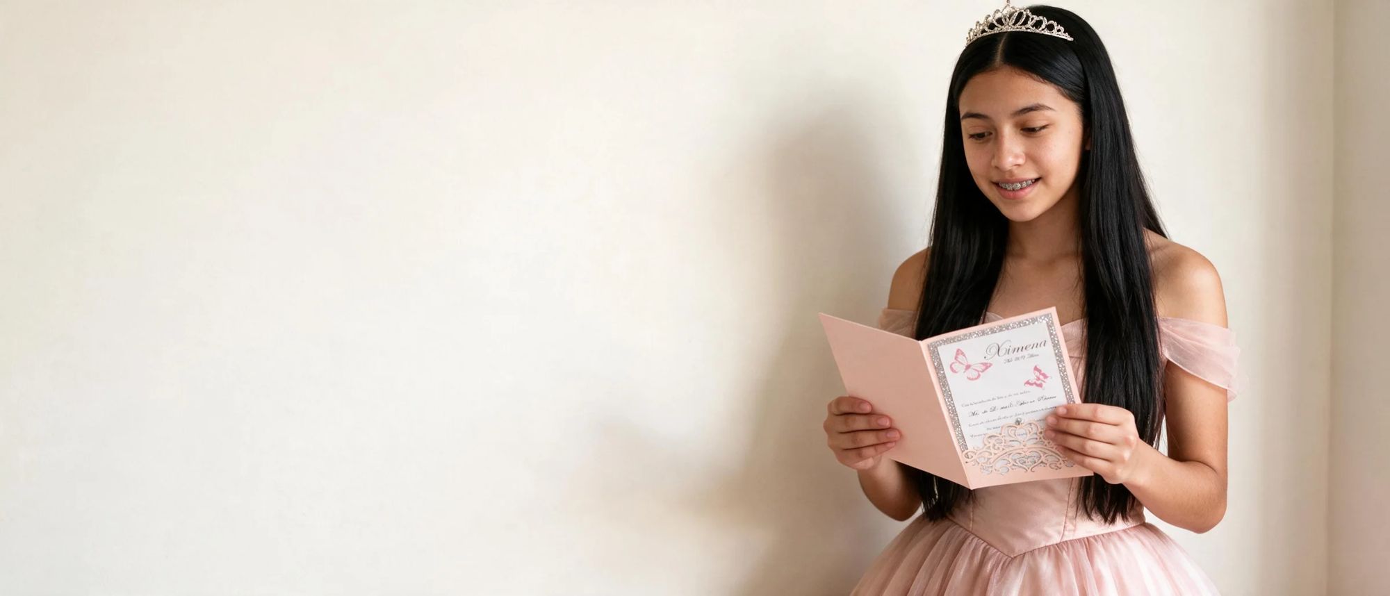 Quinceañera con vestido rosa palo leyendo su invitación de mariposas con corte láser